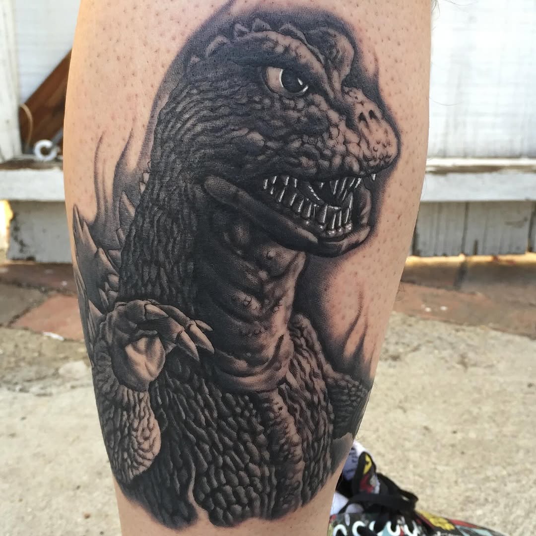 Black-and-grey Godzilla portrait tattoo, thigh