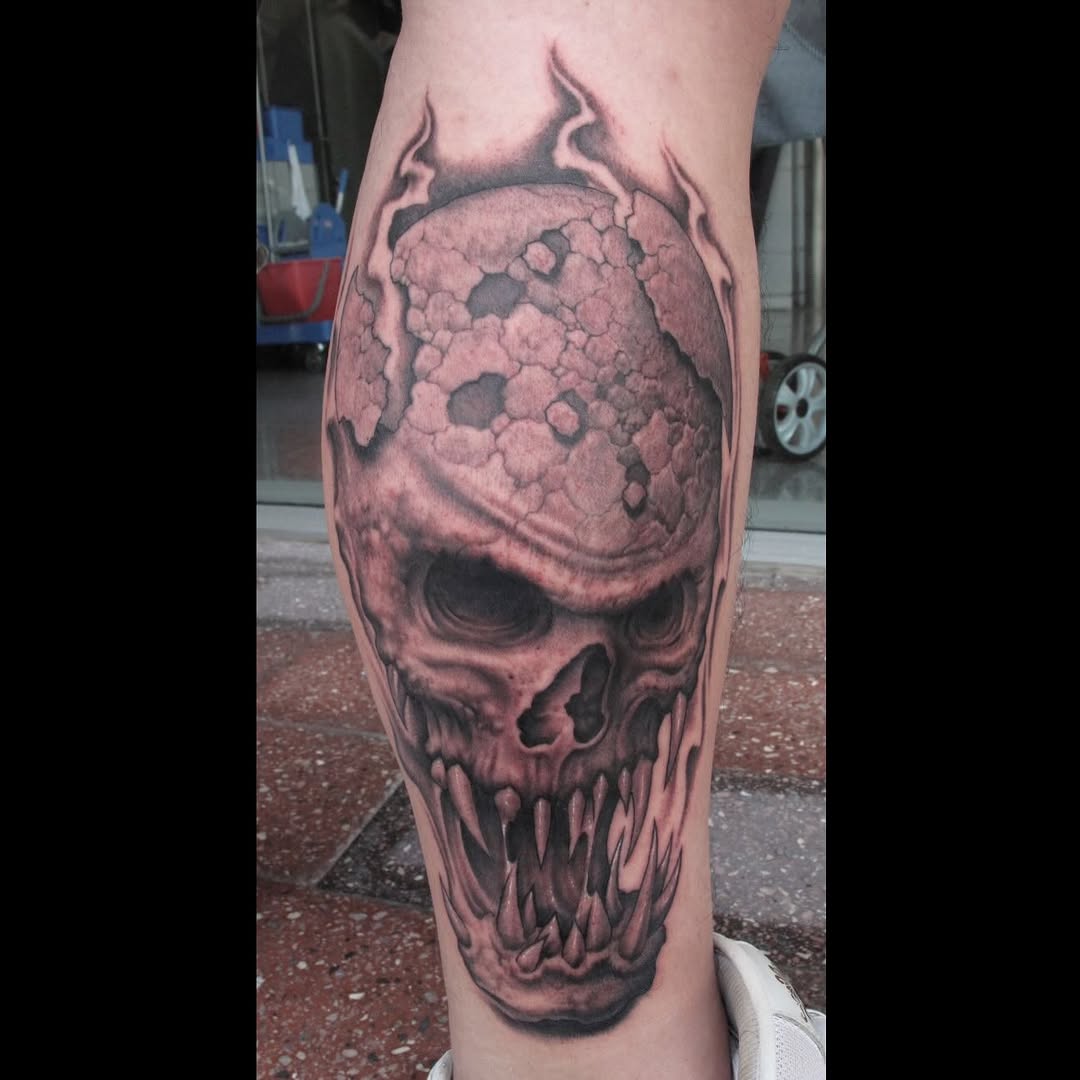 Skull with flaming horns, black-and-grey calf tattoo