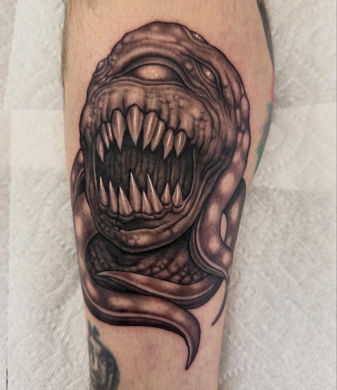 Monster creature with fangs and serpent, arm tattoo