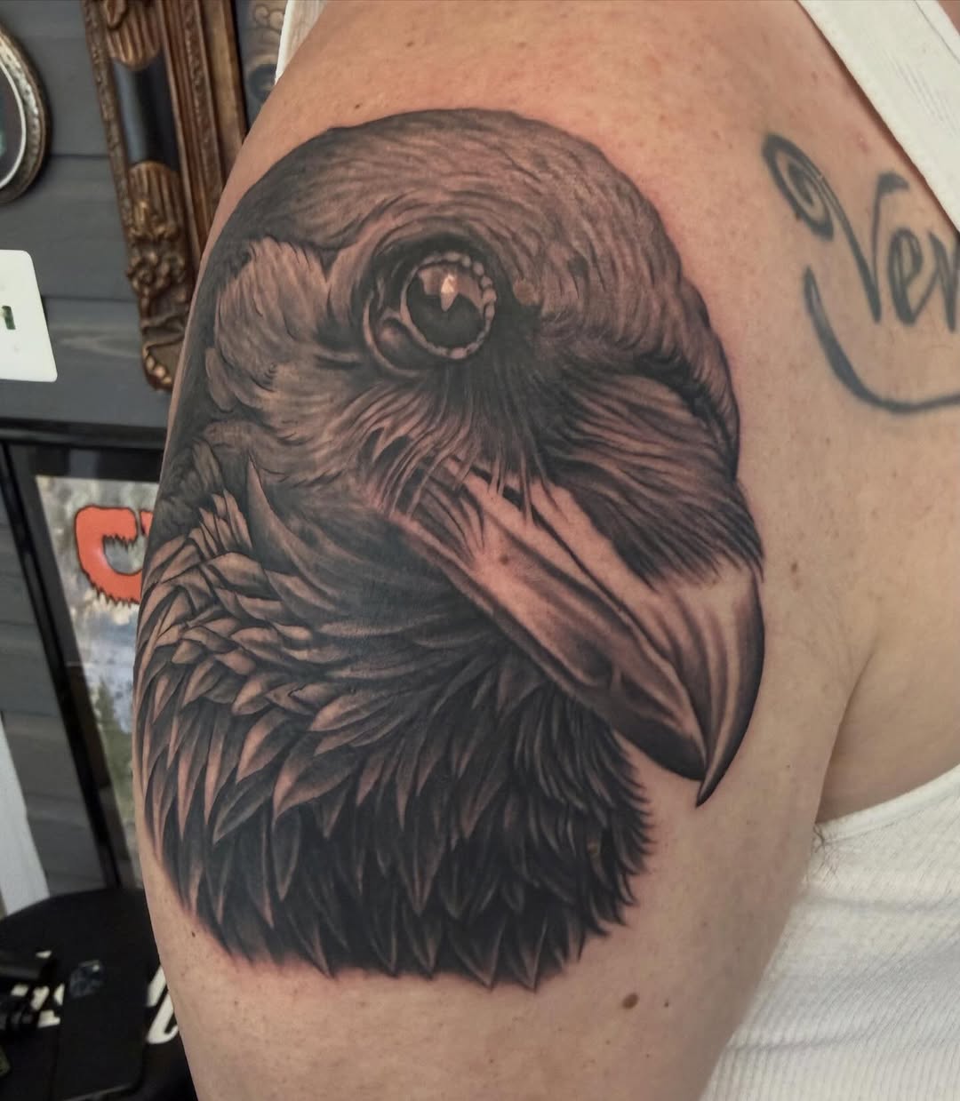 Black-and-grey raven portrait tattoo, shoulder
