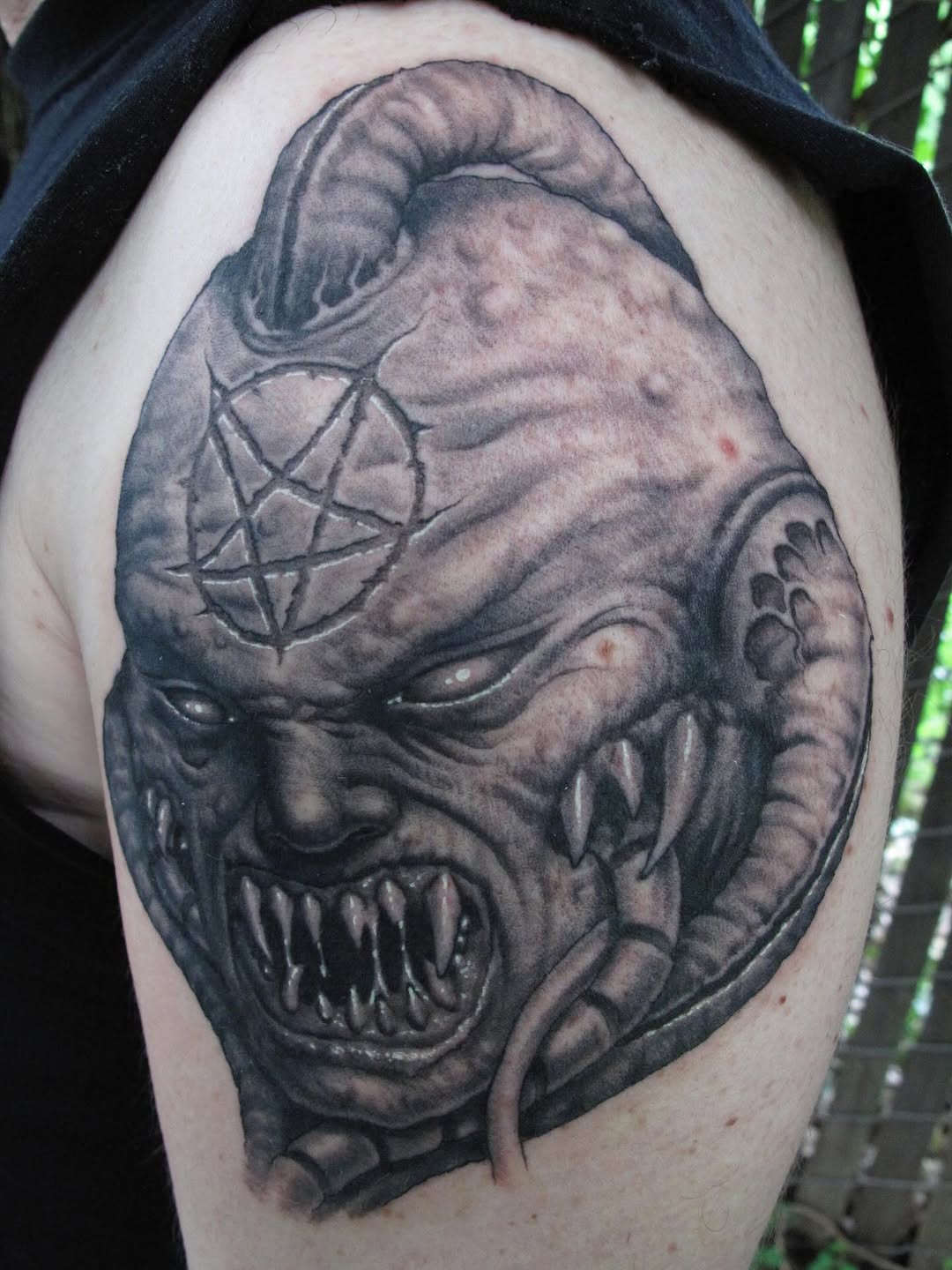 Black-and-grey demon skull shoulder tattoo