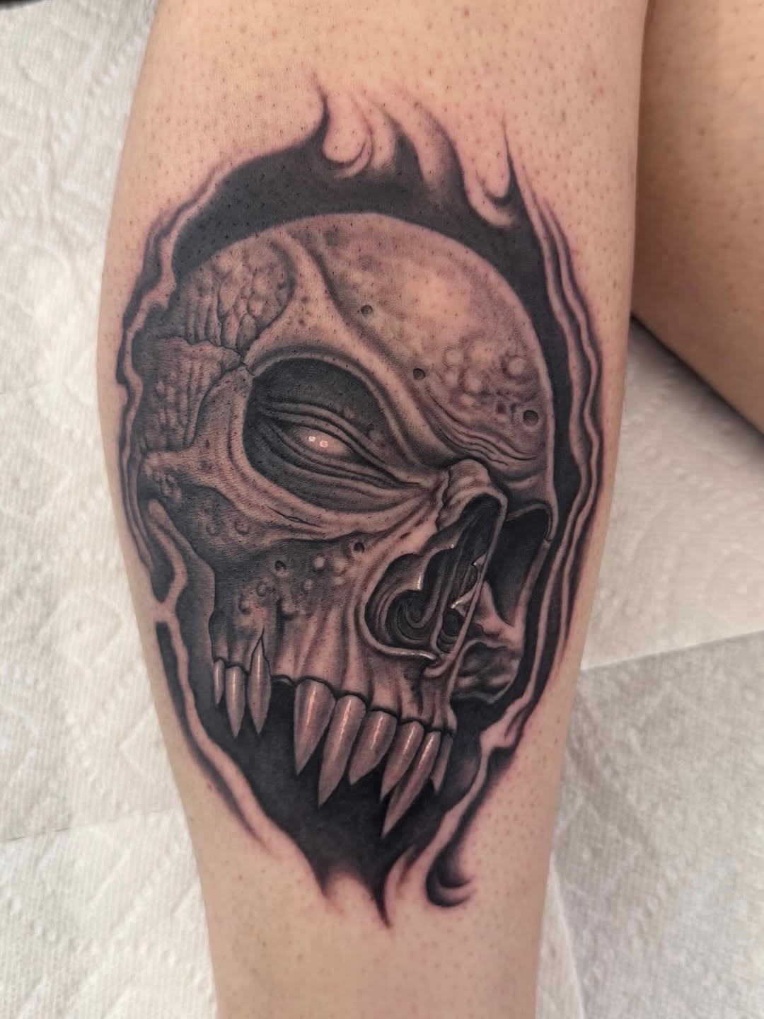 Skull portrait with fire, black-and-grey calf tattoo