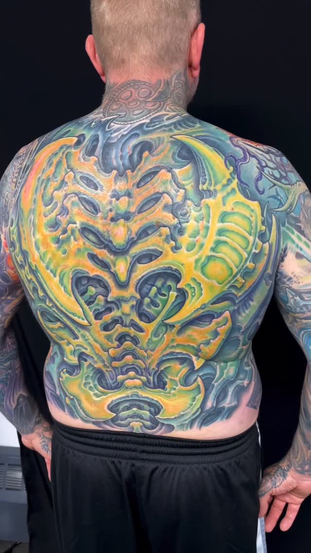 Biomechanical back piece with yellow and blue organic forms