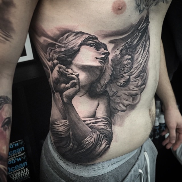 Black-and-grey praying angel tattoo on ribs