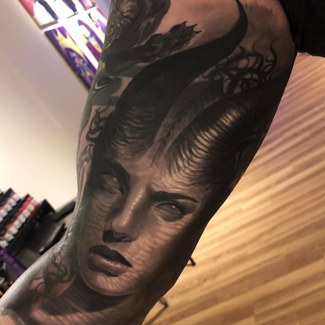 Black-and-grey demon woman portrait, forearm