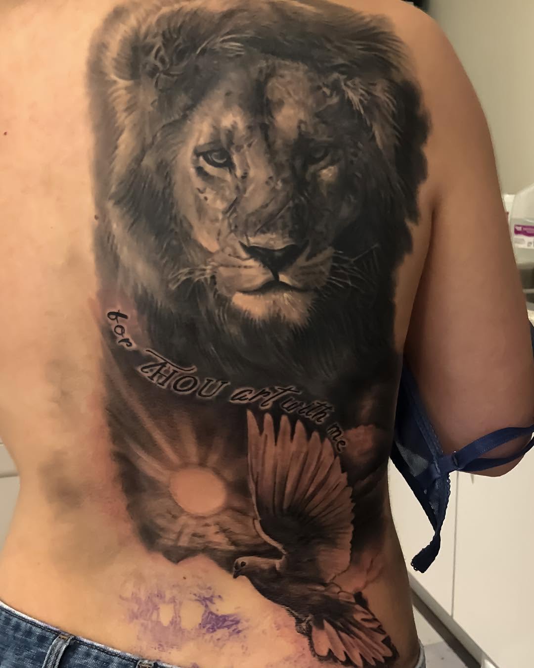 Black-and-grey lion and dove back tattoo