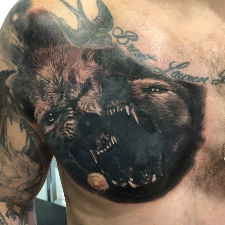 Black-and-grey snarling wolf chest tattoo