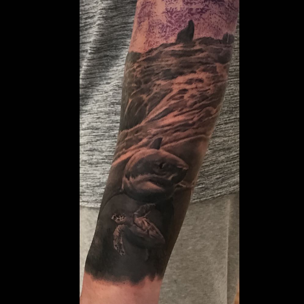 Black-and-grey shark and sea turtle forearm tattoo