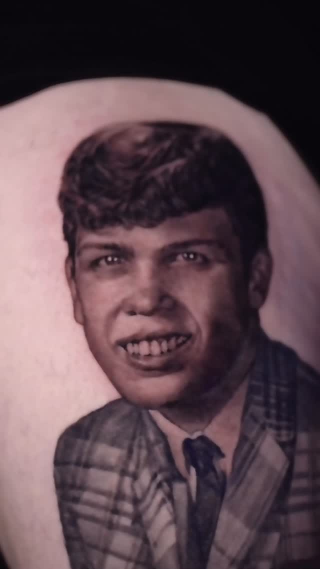 Black-and-grey portrait tattoo of young man