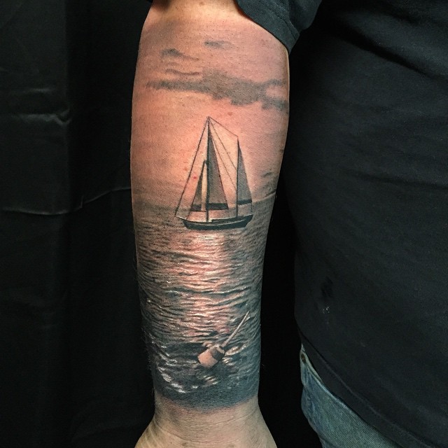 Black-and-grey sailboat at sea, forearm