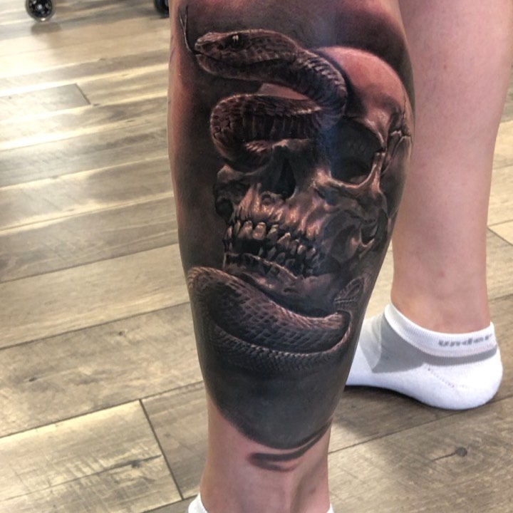 Black-and-grey snake and skull tattoo, calf