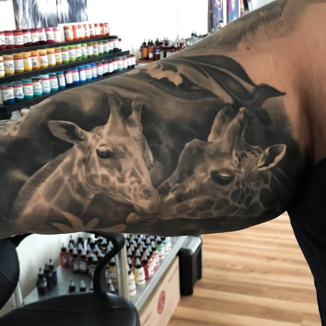 Black-and-grey giraffe pair tattoo, bicep