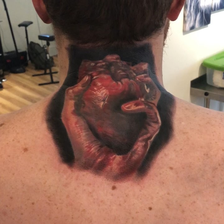 Realistic hand holding heart tattoo, neck