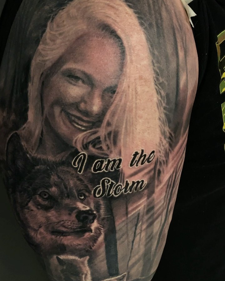Black-and-grey memorial portrait with wolf, arm
