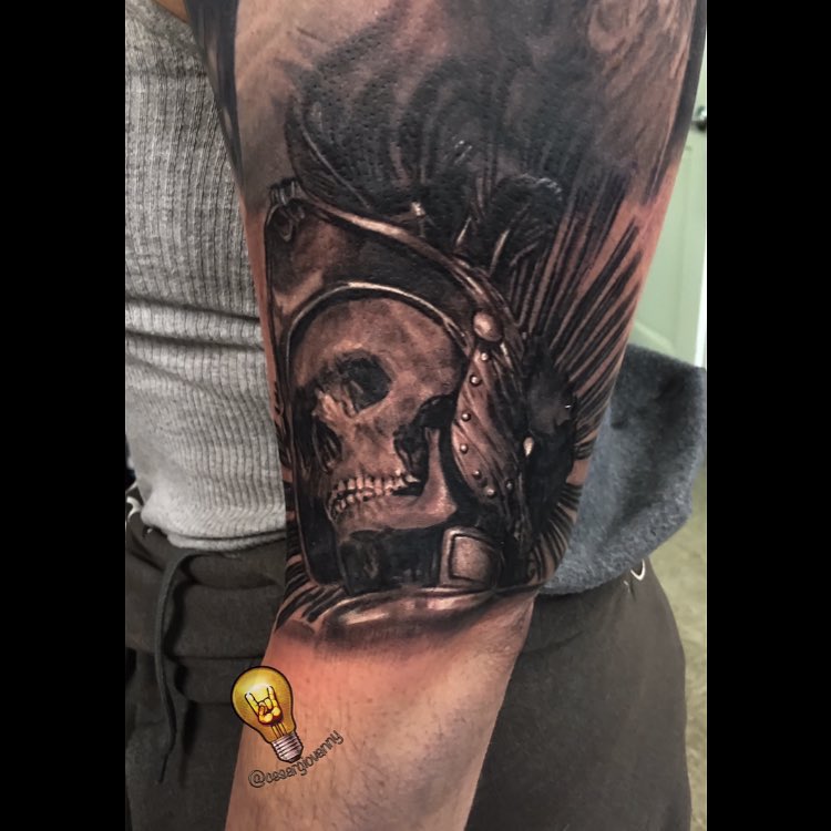 Black-and-grey skull warrior tattoo on arm
