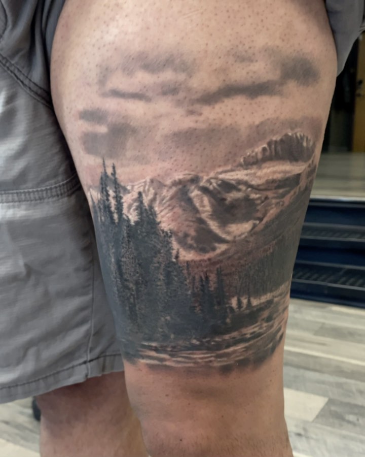 Black-and-grey mountain scenery tattoo, thigh