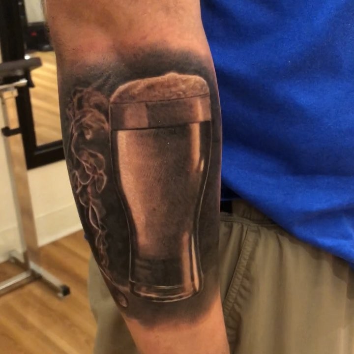 Black-and-grey beer pint tattoo, forearm