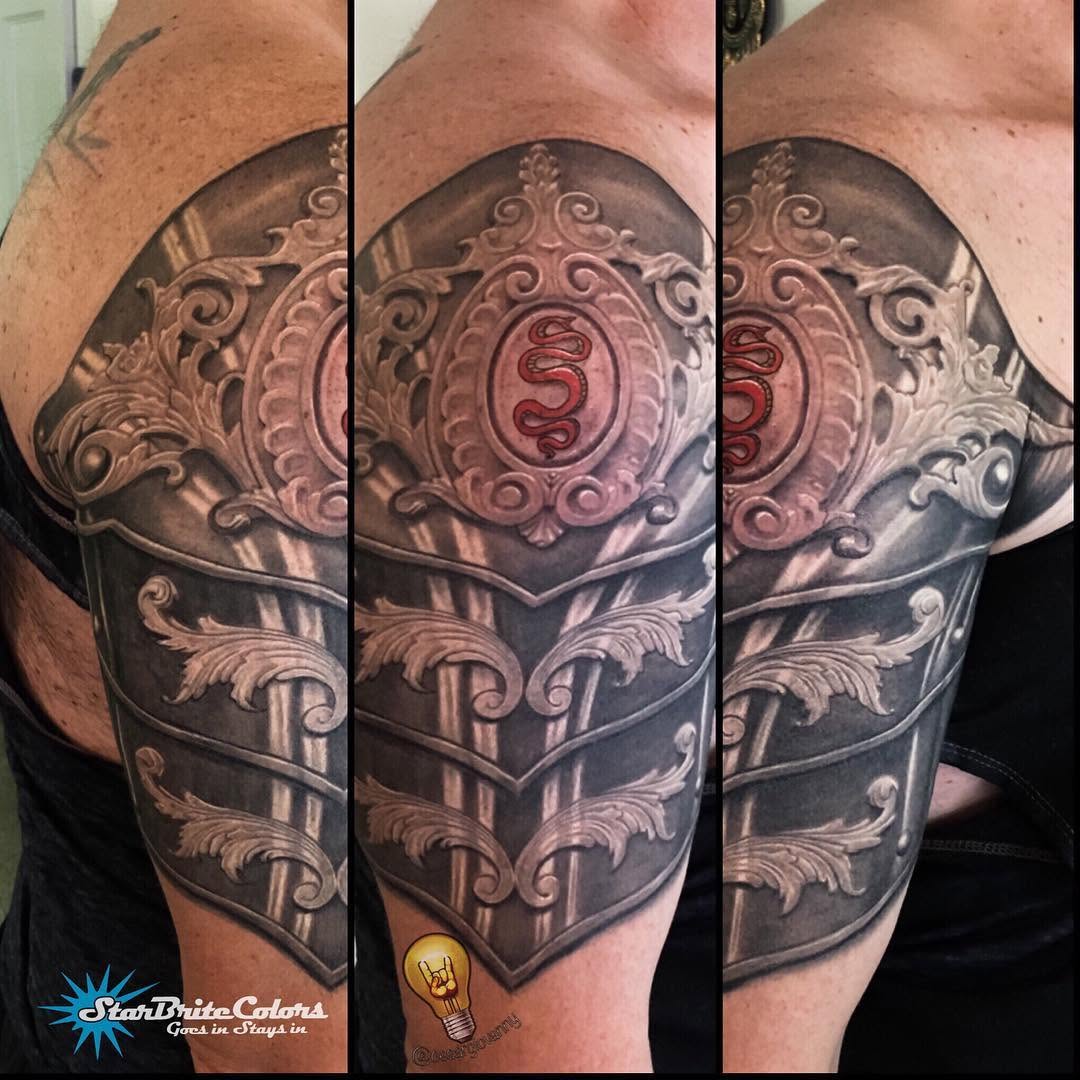 Ornate armor shoulder tattoo with crest, half-sleeve