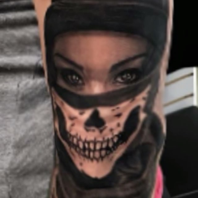 Black-and-grey woman with skull mask tattoo