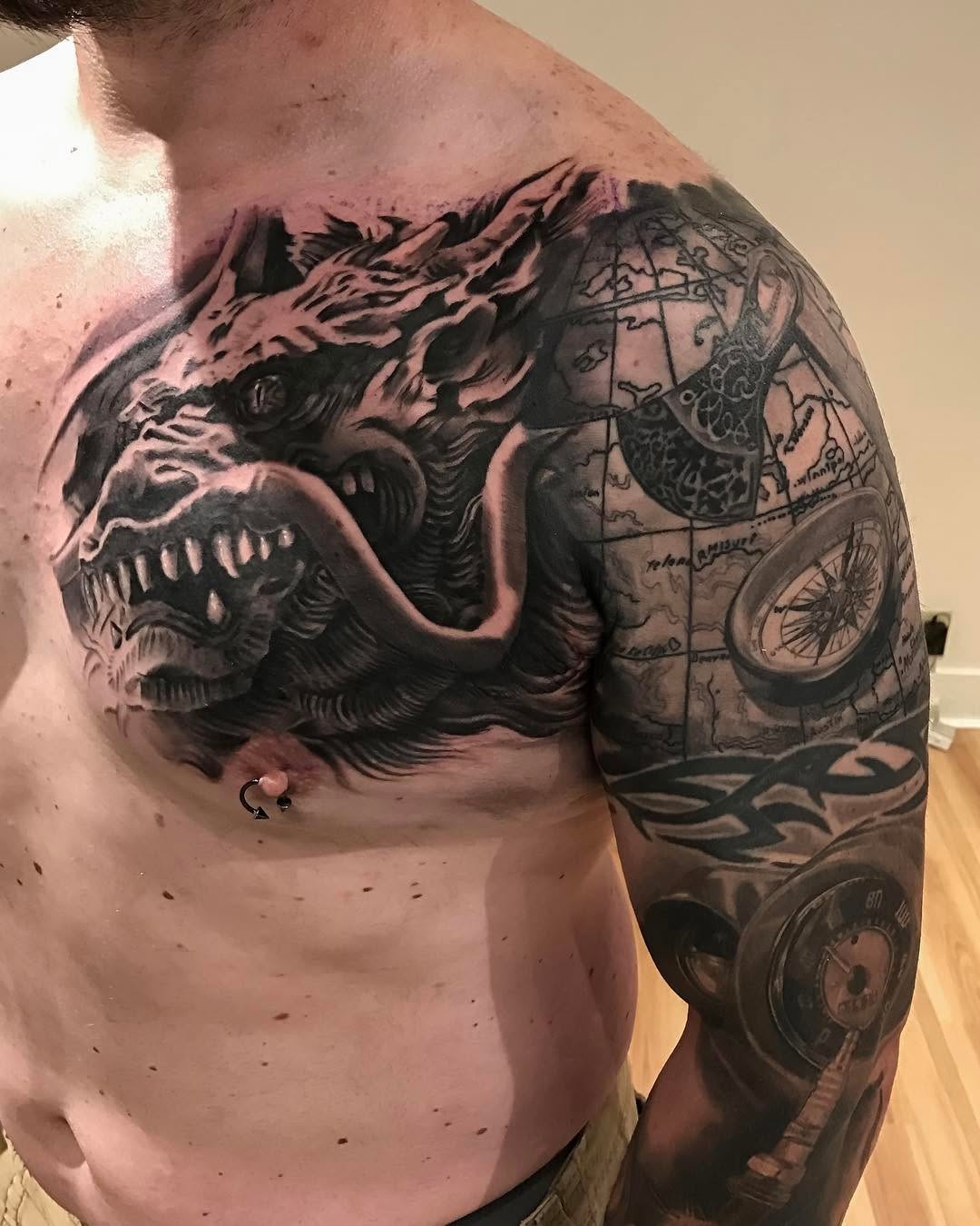 Black-and-grey wolf chest tattoo with map sleeve