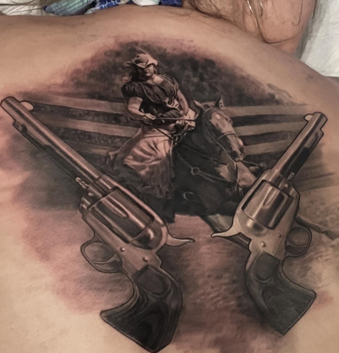 Black-and-grey cowgirl and revolvers back tattoo