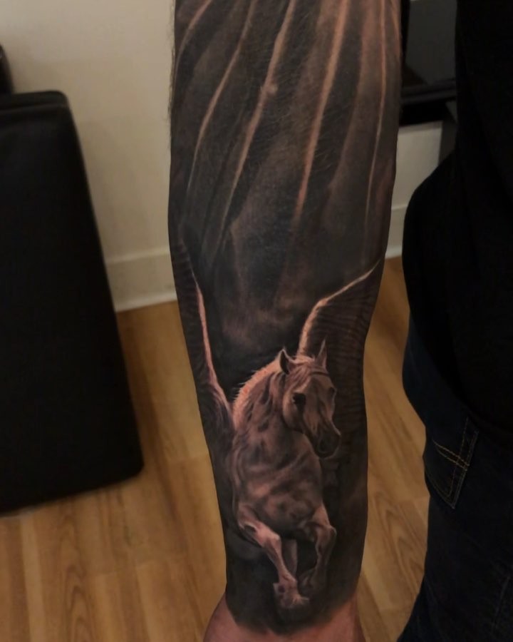 Black-and-grey Pegasus forearm tattoo