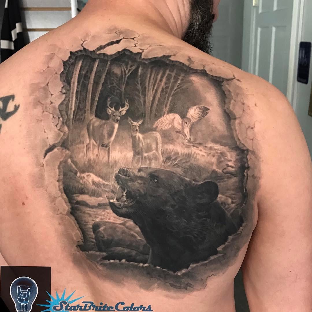 Black-and-grey forest scene back tattoo, bear & deer