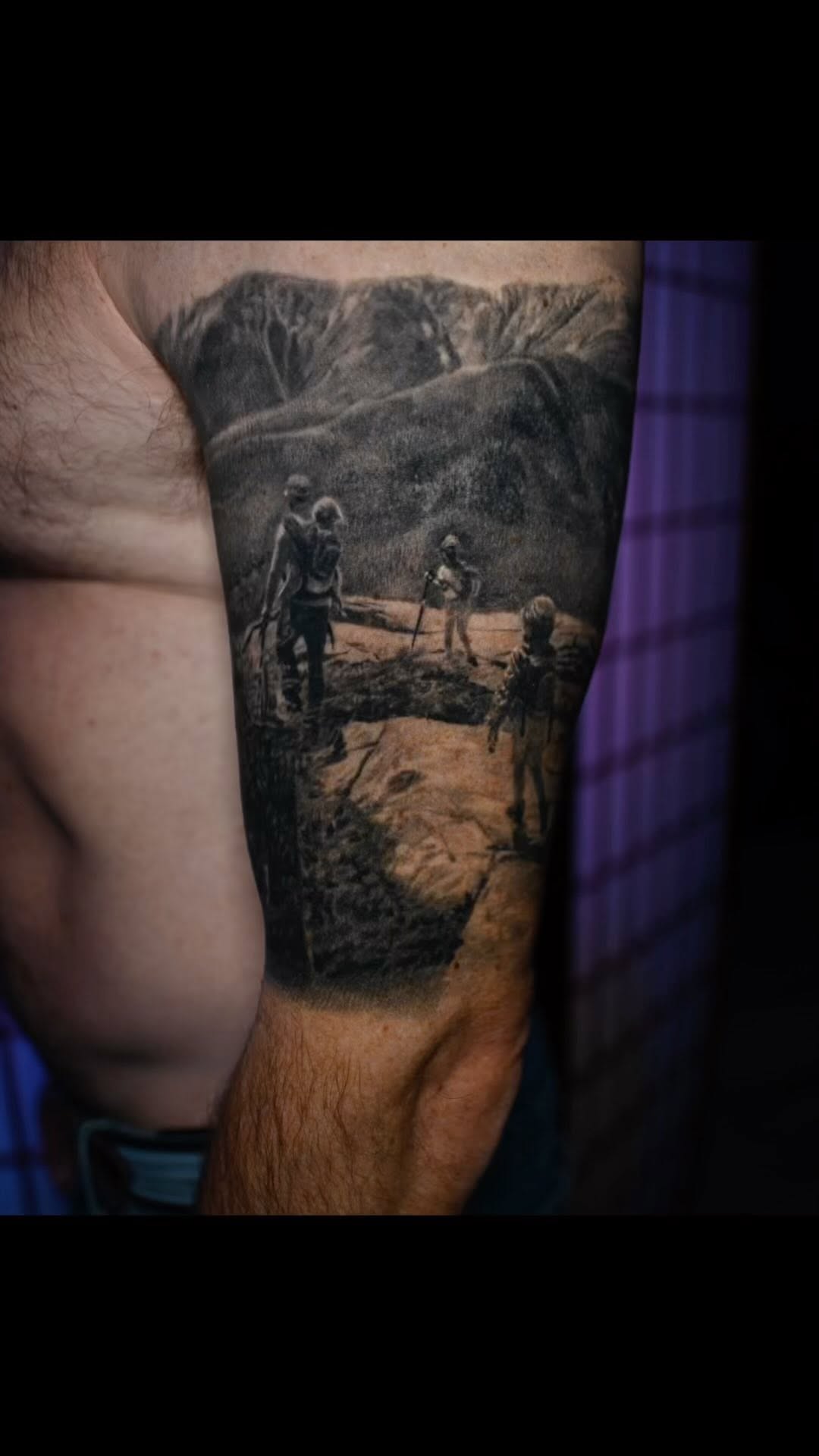 Black-and-grey hiking scene tattoo, bicep