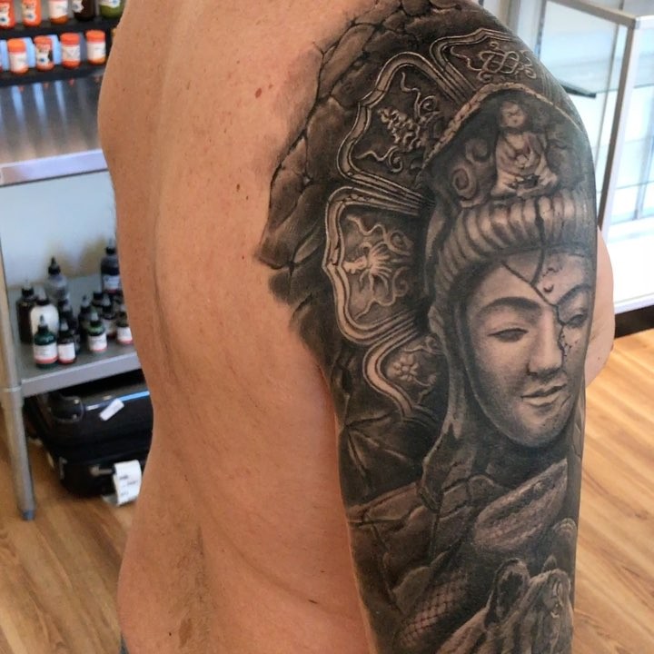 Black-and-grey Buddha stone statue tattoo, arm