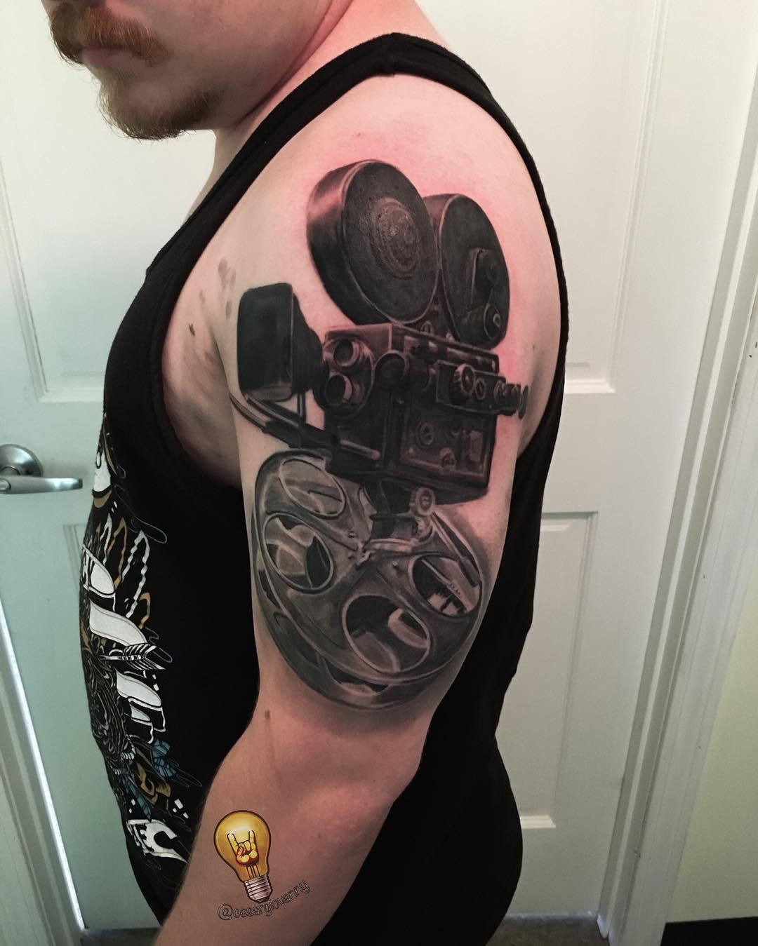 Black-and-grey vintage movie camera tattoo, arm