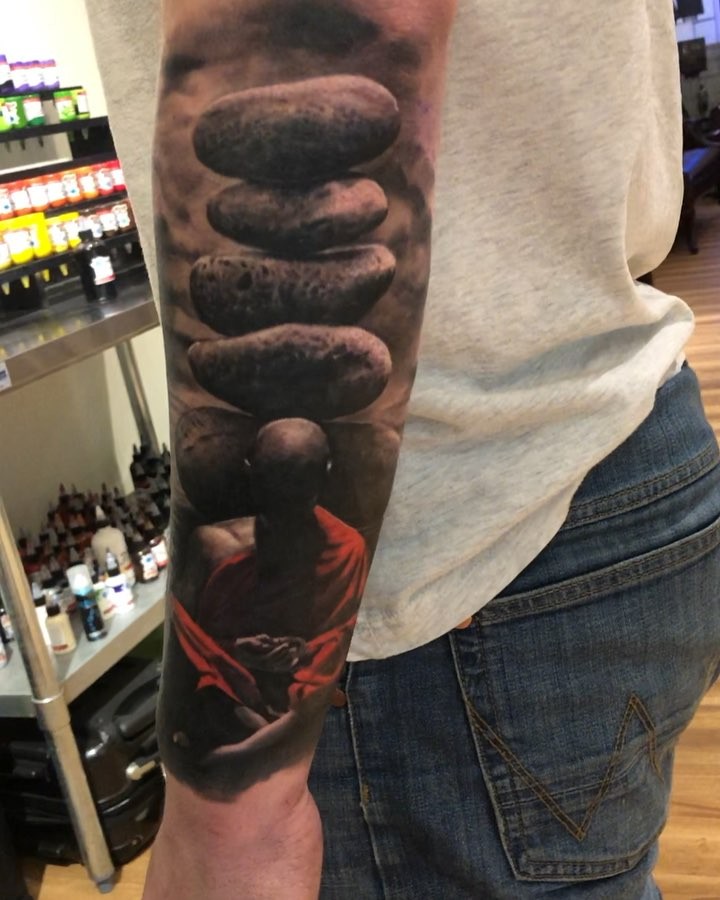 Realistic Buddha and stacked stones forearm tattoo