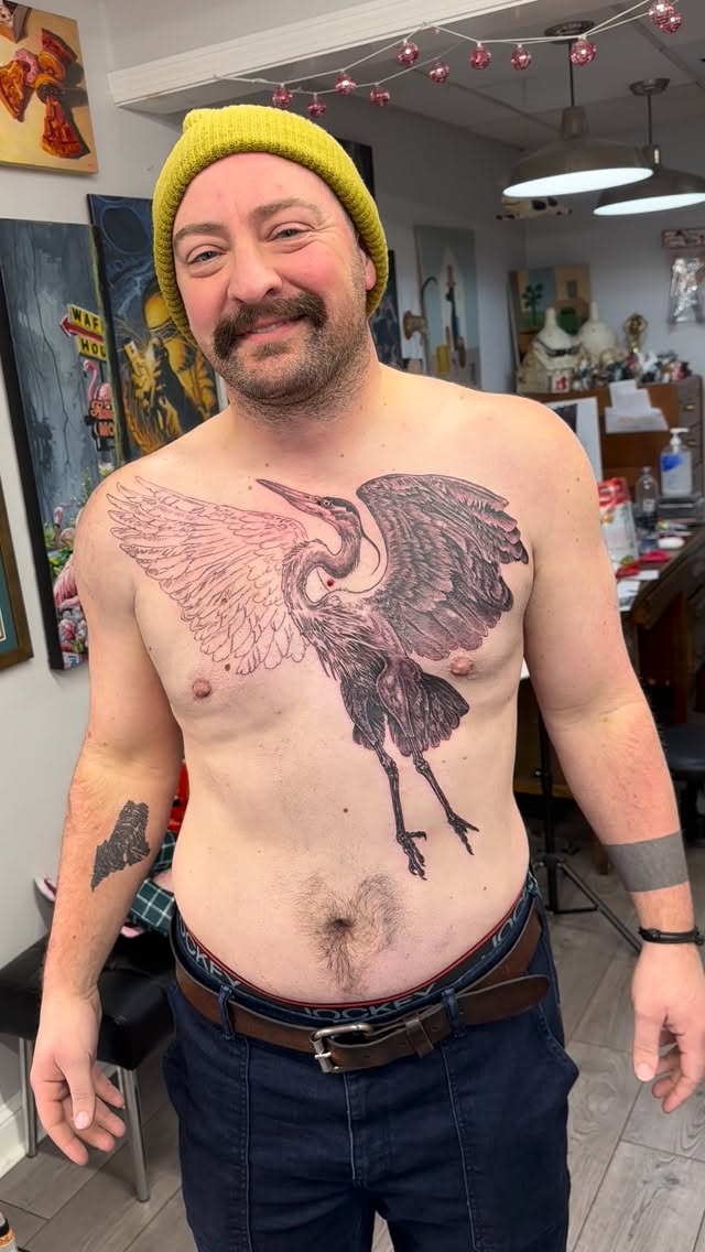Black-and-grey crane chest tattoo