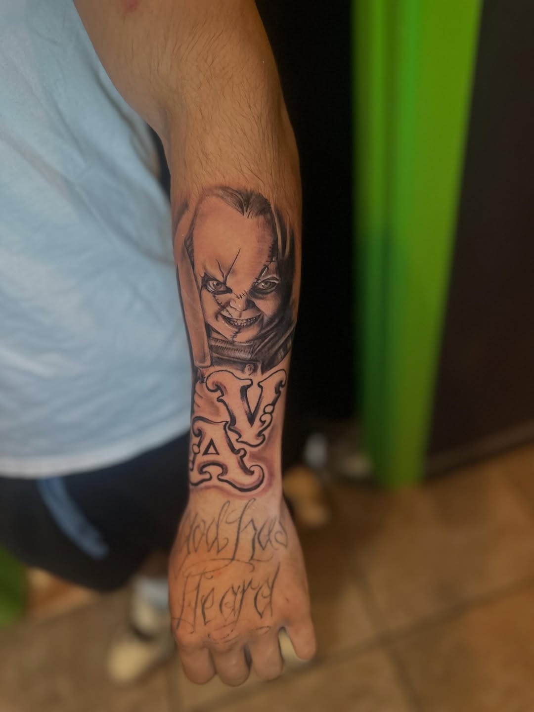 Chucky doll portrait with script text, forearm