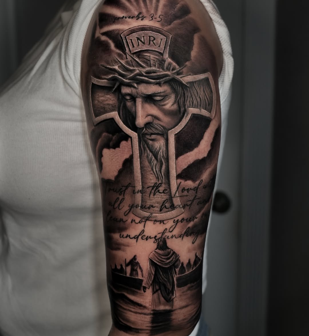 Black-and-grey Jesus portrait cross tattoo, upper arm