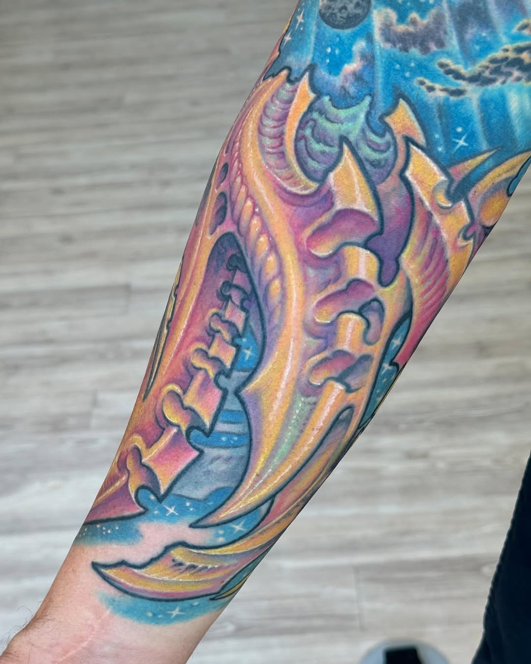 Colorful biomechanical forearm sleeve with cosmic sky