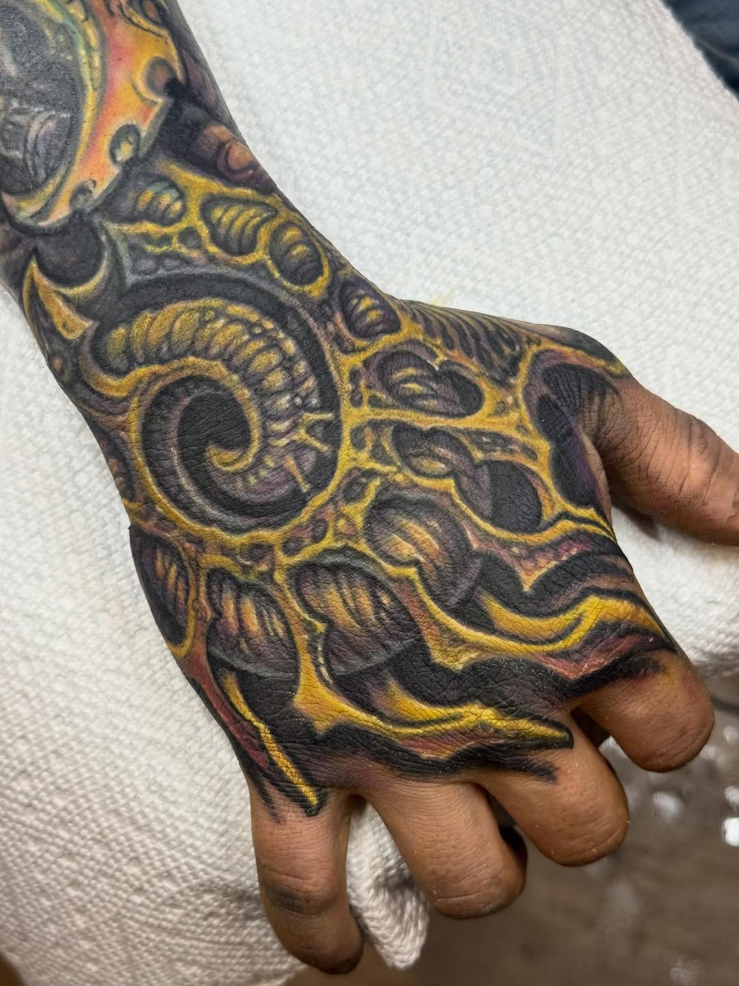 Biomechanical hand tattoo in yellow and purple