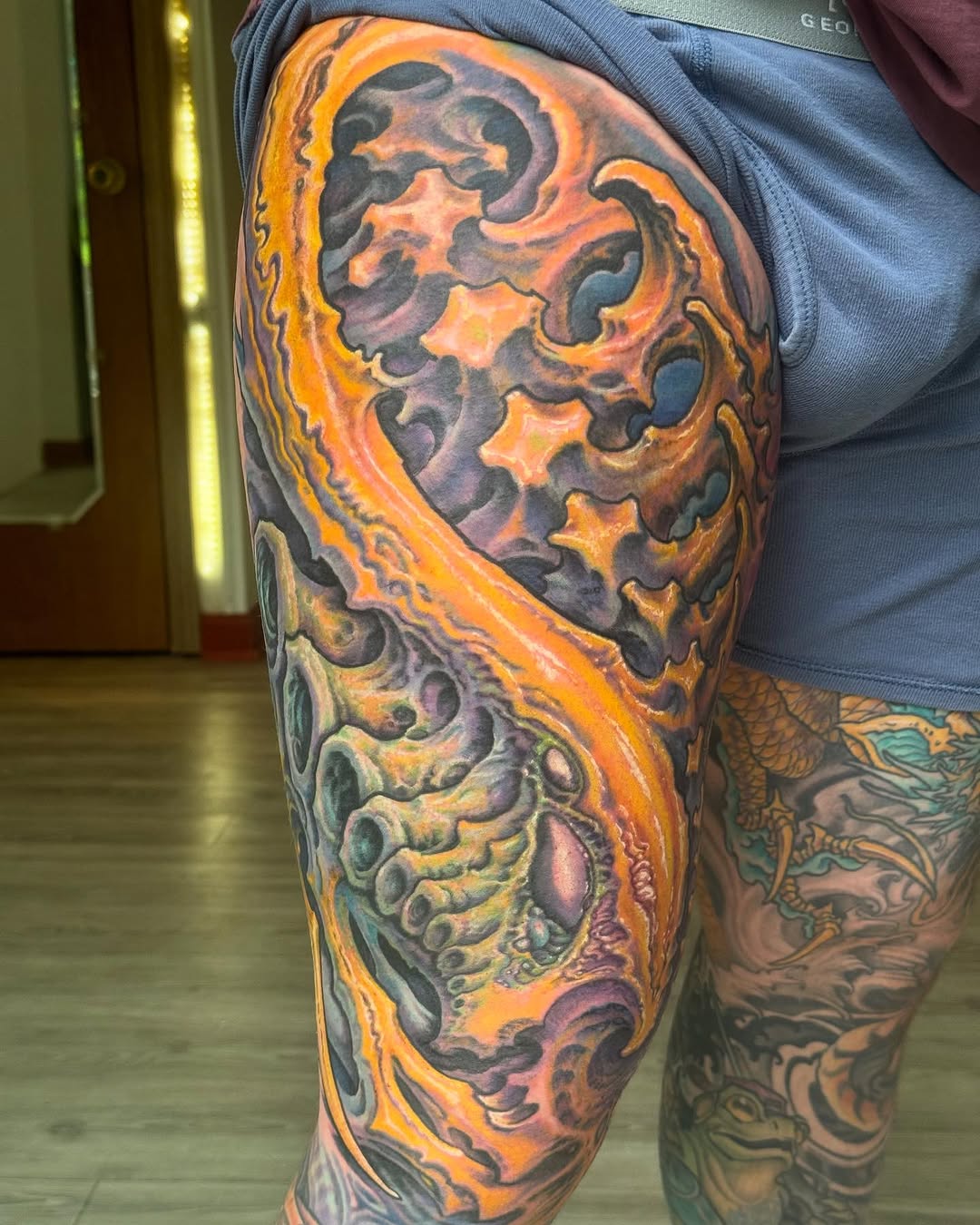 Biomechanical thigh tattoo in orange and purple