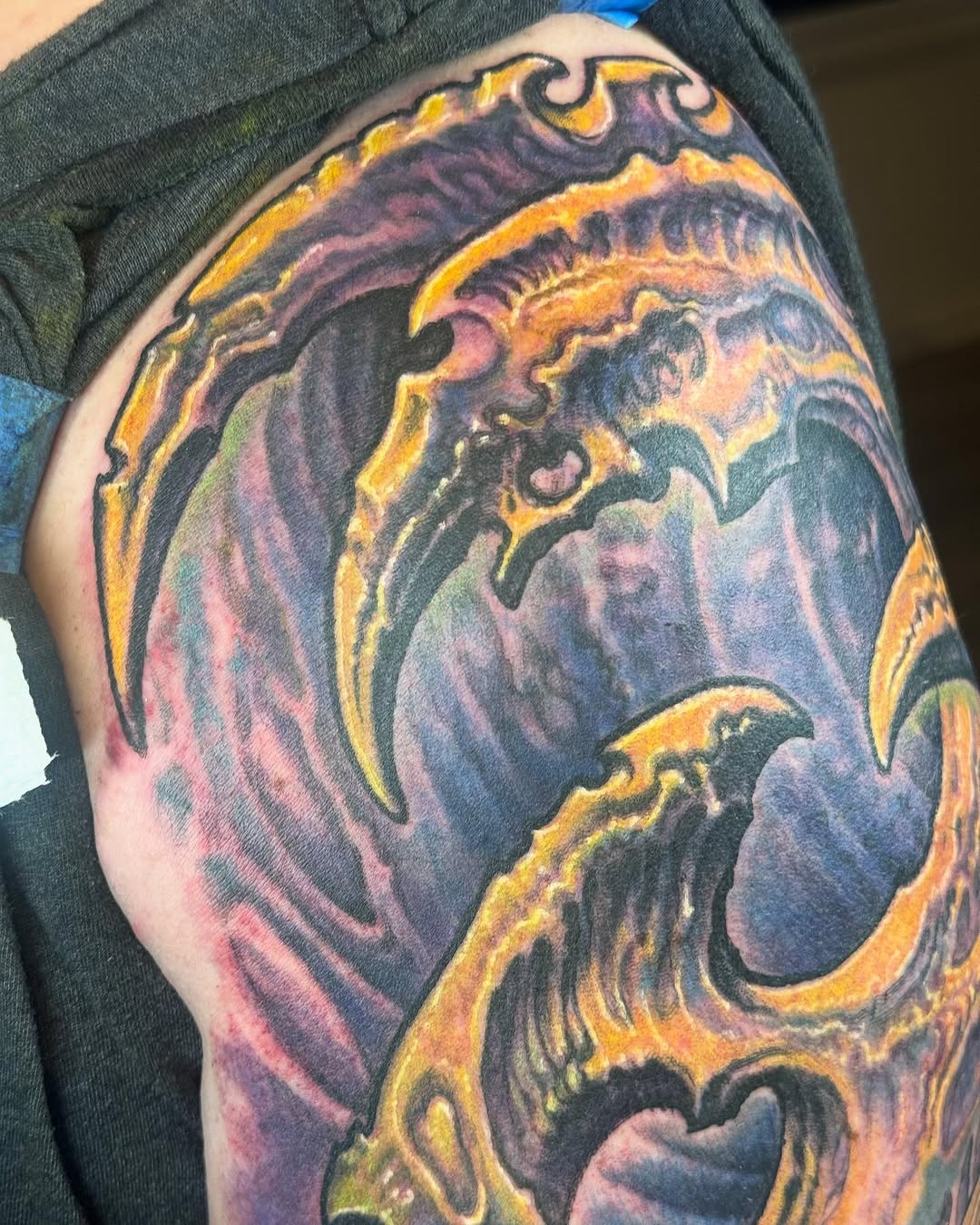 Biomechanical shoulder tattoo in purple and gold