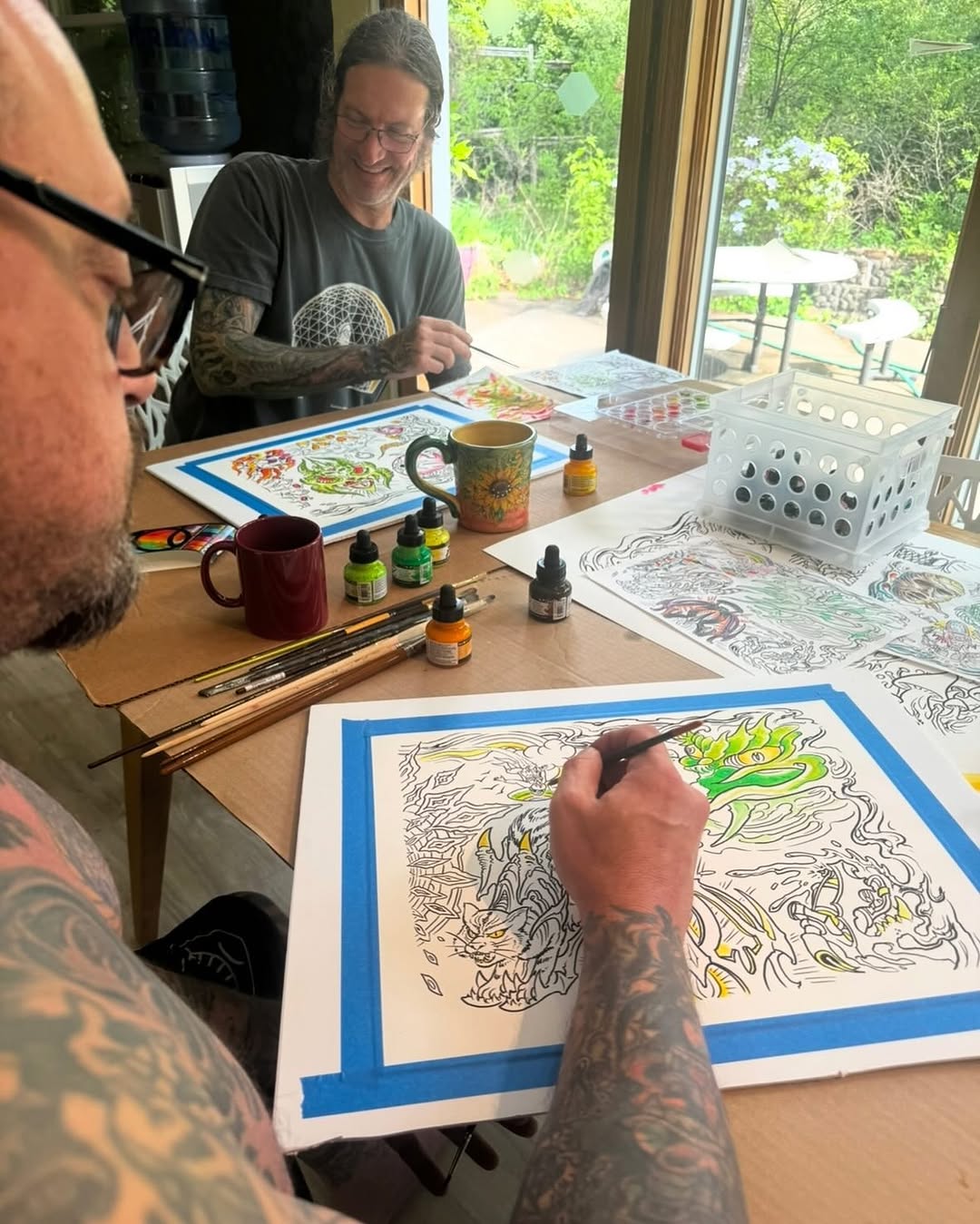 Artists painting tattoo flash sheets in studio