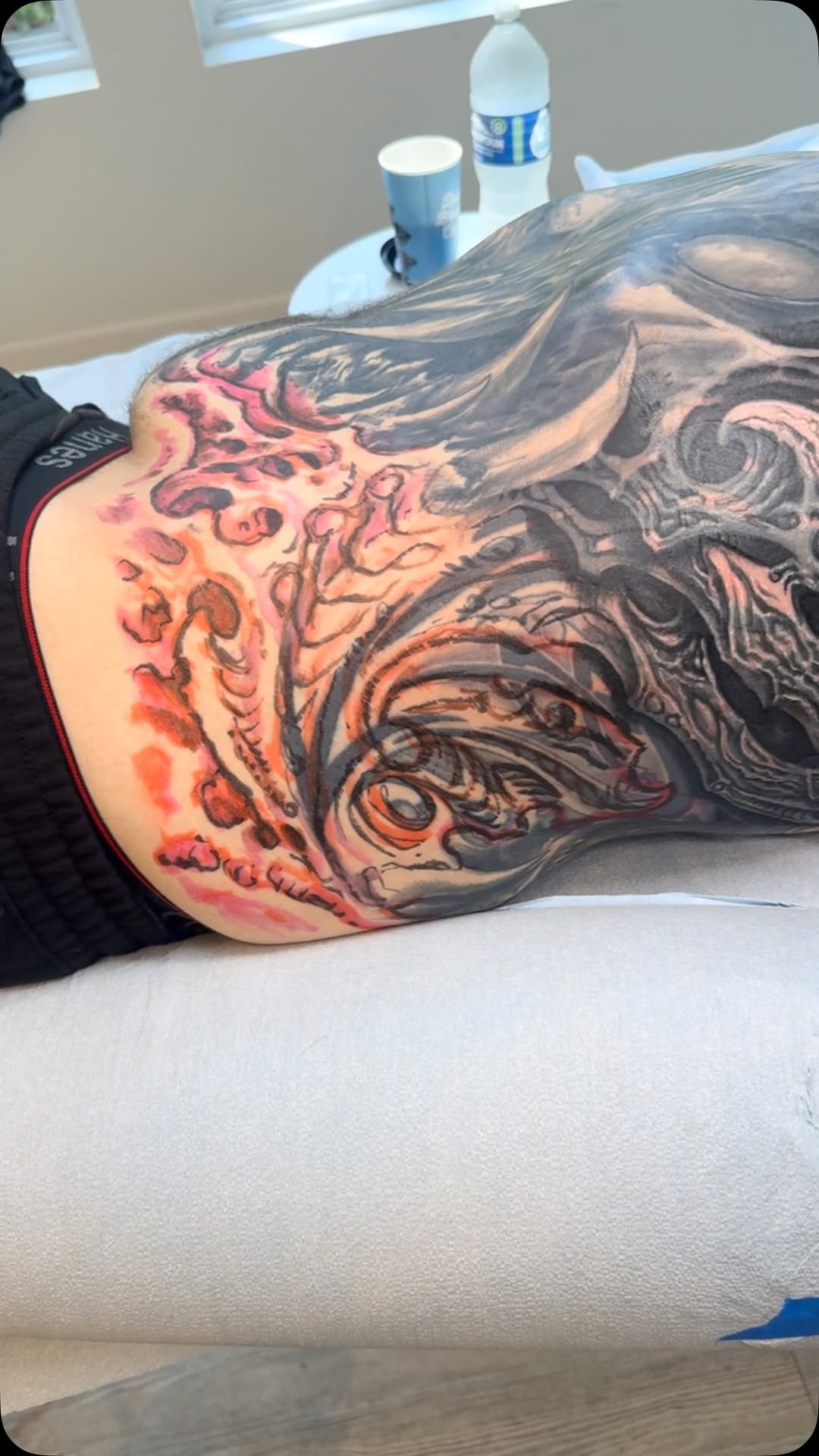 Black-and-grey biomechanical back coverup in progress