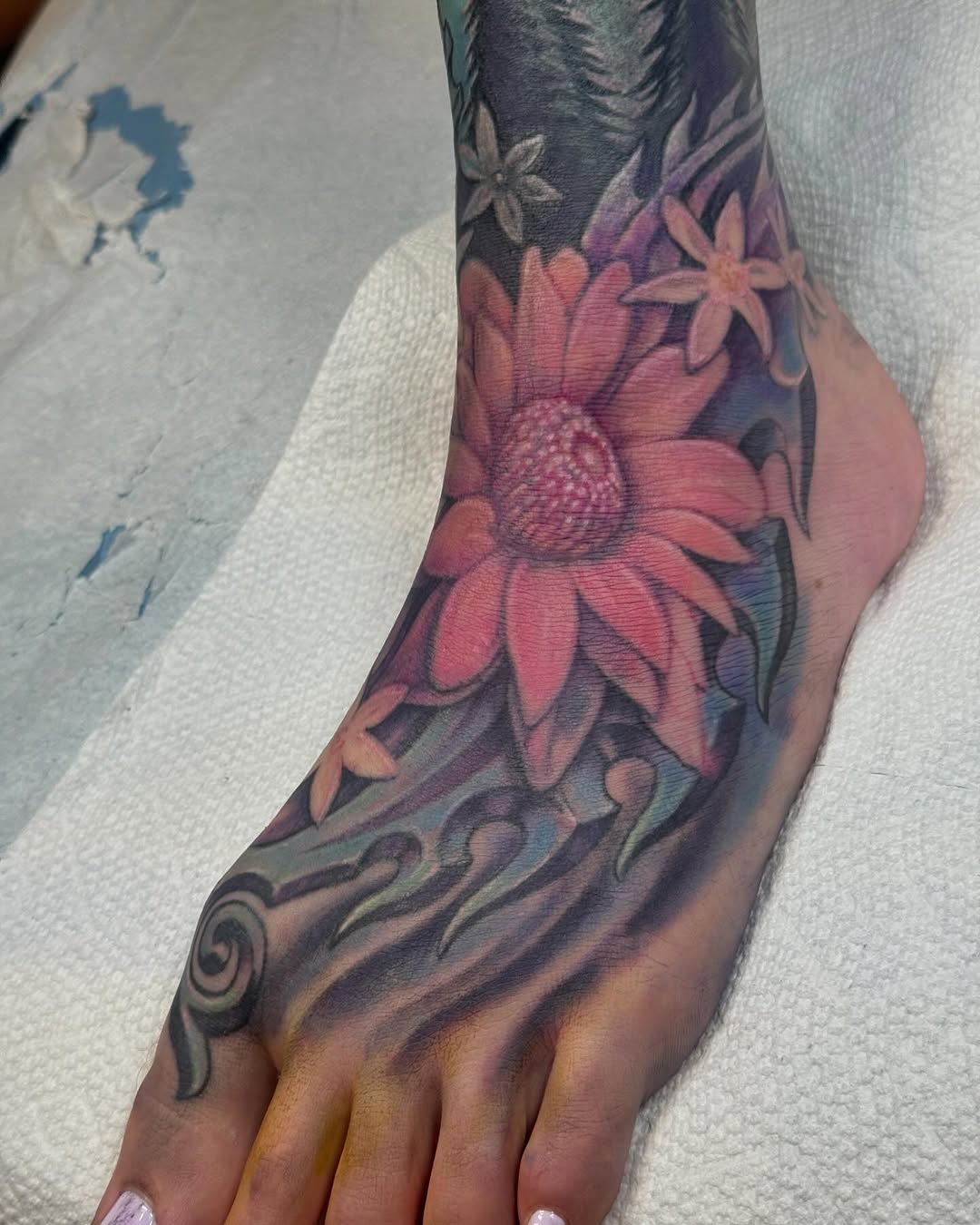 Pink flannel flower foot tattoo in color