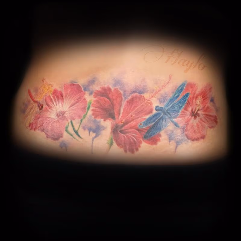 Lower back custom, realistic style tattoo with hibiscus flowers, and dragonflies with watercolor accents