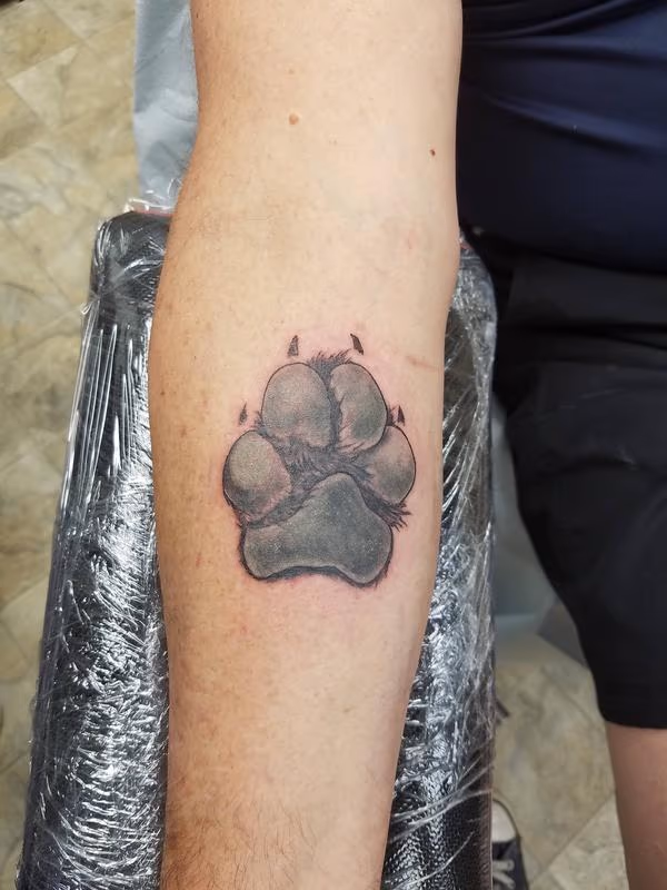 "A stunning black and grey realism tattoo featuring a detailed depiction of a dog paw."