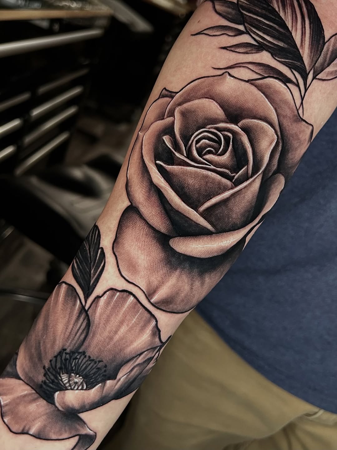 Realistic rose and floral half-sleeve tattoo, black-and-grey
