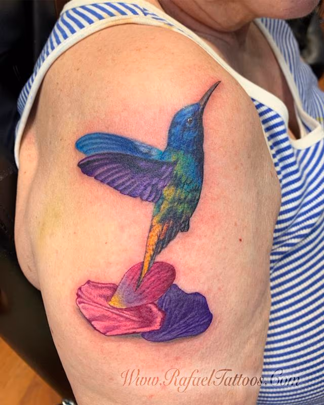 Realistic hummingbird with flower petals tattoo on aged skin
