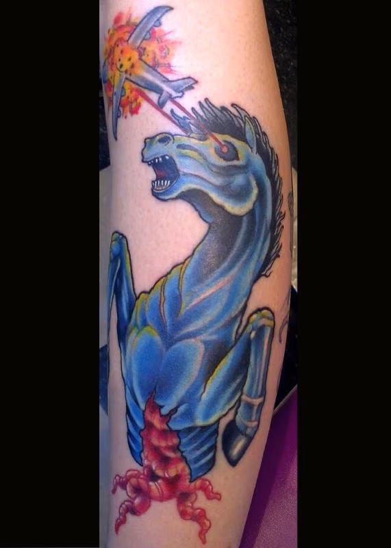 A disemboweled horse shooting lasers at an airplane tattoo.