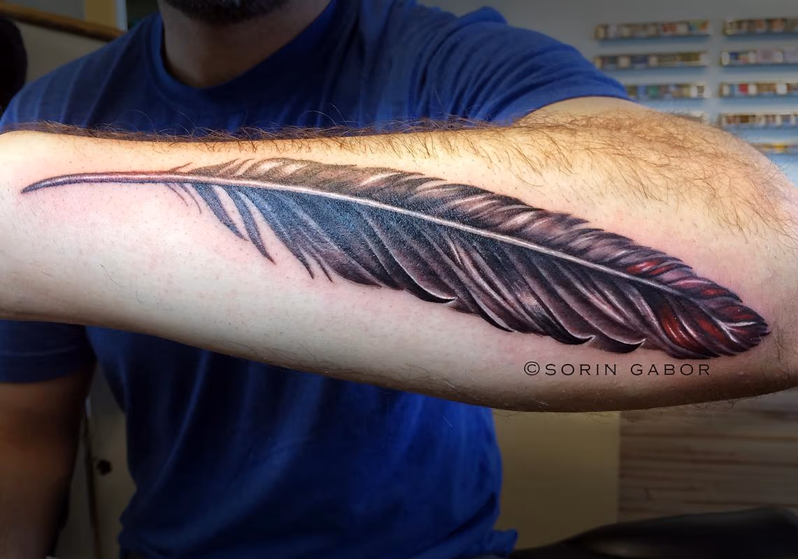 Realistic black and gray with color accent feather on forearm