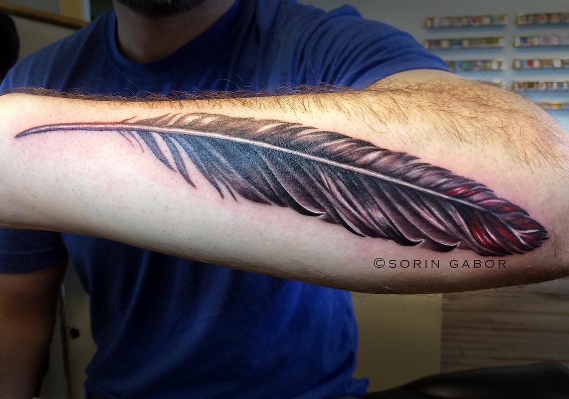 Realistic black and gray with color accent feather on forearm