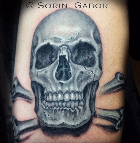 Realistic black and opaque gray skull tattoo on forearm