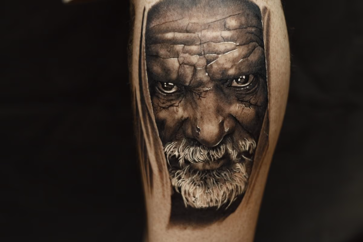 Black and grey portrait tattoo of an older man.